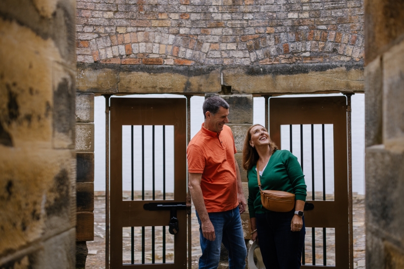Two people standing in front of prison cell doors looking around