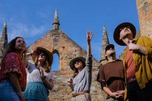 Tour group pointing upwards with a church ruin background